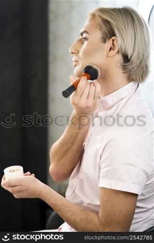 man wearing make up using powder