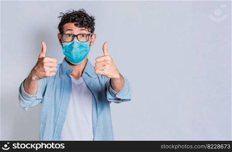 Man wearing medical mask and giving thumbs up, Isolated person wearing medical mask giving thumbs up.