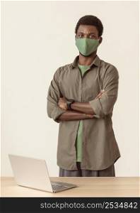 man wearing medical mask standing his laptop