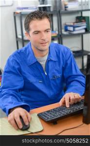 Man wearing overalls, on computer