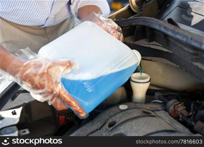 Man wearing plastic gloves, refilling windscreen wiper fluid in his car