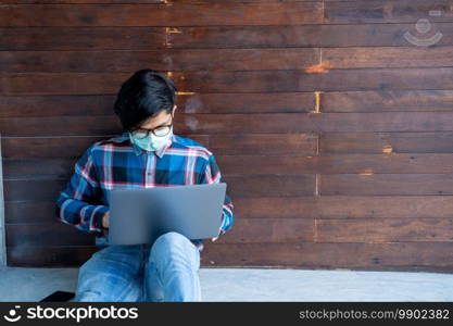 Man wearing protective mask to Protect Against Covid-19 working and watching video streaming at home after coronavirus pandemic,Coronavirus has turned into a global emergency.