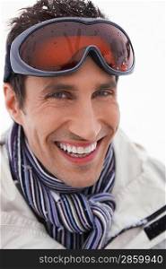 Man wearing ski goggles smiling portrait close up