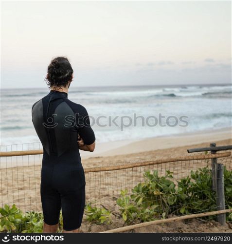 man wearing surfer clothes looking sea