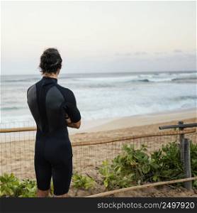 man wearing surfer clothes looking sea