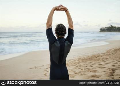 man wearing surfer clothes stretches