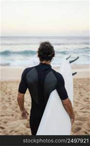 man wearing surfer clothes walking sand