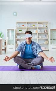 Man wearing virtual reality VR glasses meditating on floor at home. Man wearing virtual reality VR glasses meditating on floor at ho