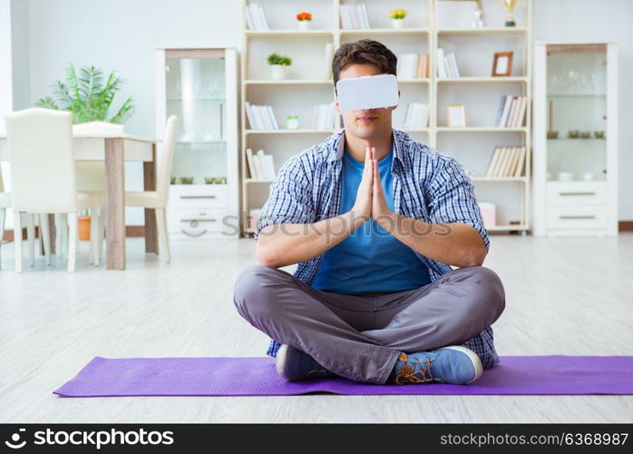 Man wearing virtual reality VR glasses meditating on floor at home. Man wearing virtual reality VR glasses meditating on floor at ho