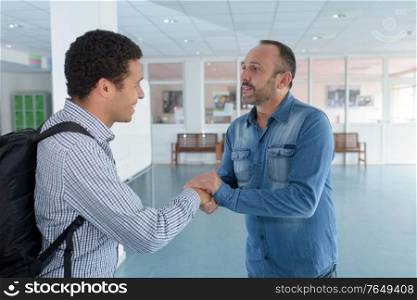 man welcoming young visitor with a warm handshake