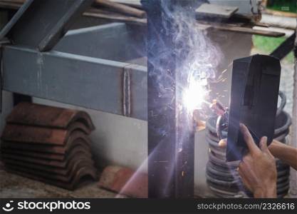 Man welder doing a metal staircase structure in a residential building using a welding machine.