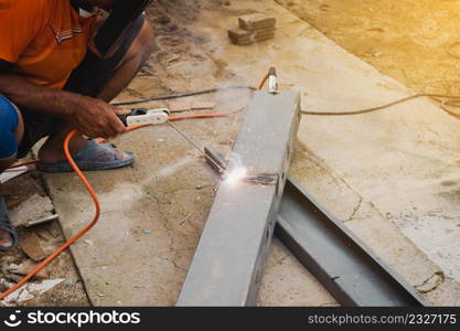 Man welder doing a metal staircase structure in a residential building using a welding machine.