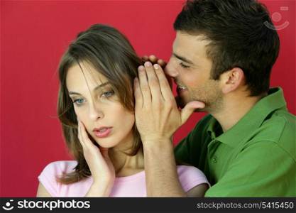 Man whispering a secret to a young woman