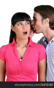 Man whispering into a woman&rsquo;s ear