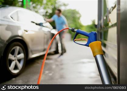 Man wipes a car with a rag, hand auto wash station. Car-wash industry or business. Male person cleans his vehicle from dirt outdoors. Man wipes a car with rag, hand auto wash station