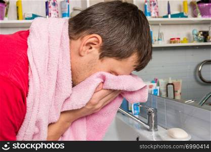 Man wipes his face with a towel in the bathroom