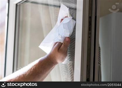 Man wiping window using paper towels, cleaning services concept. Housework and housekeeping concept