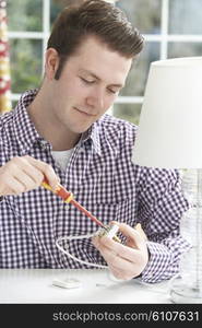 Man Wiring Electrical Plug On Lamp At Home