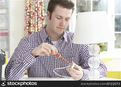 Man Wiring Electrical Plug On Lamp At Home