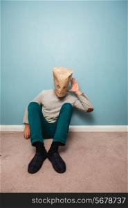 Man with a bag over his head is sitting on the floor and listening