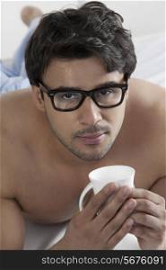 Man with a cup of coffee in bed