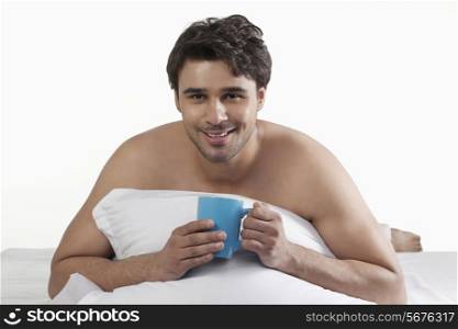 Man with a cup of coffee in bed