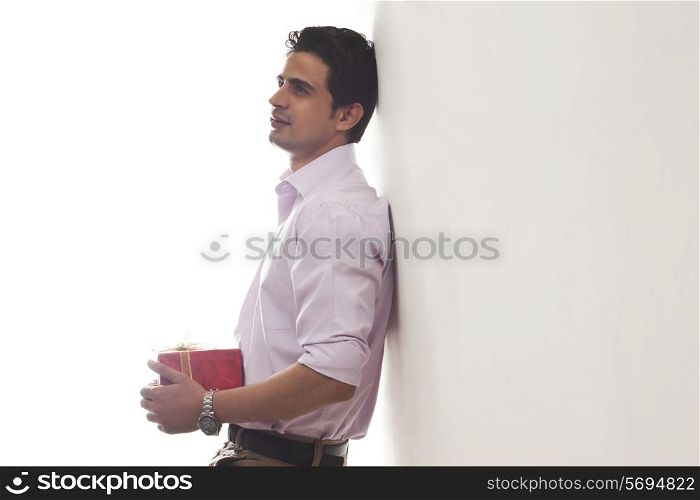 Man with a gift leaning against wall