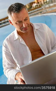 Man with a laptop by a pool