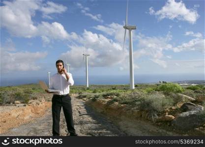 Man with a phone and laptop on a wind farm