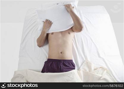 Man with a pillow covering his head