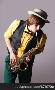 Man with a sax musical instrument on tne grey background