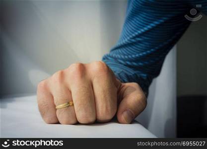 Man with a wedding ring squeezed his hand on white cloth background.