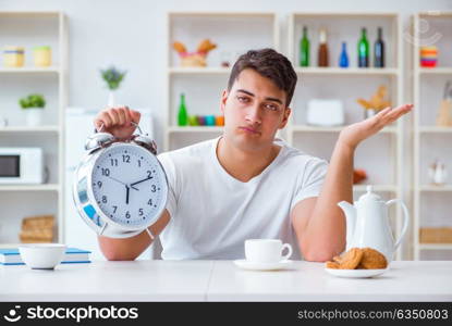 Man with alarm clock falling asleep at breakfast