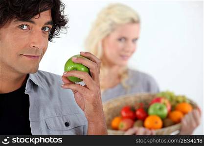 Man with apple and woman with basket in the background