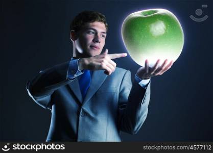 Man with apple. Young businessman holding green apple in hand
