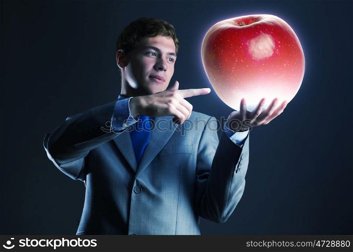 Man with apple. Young businessman holding huge apple in hand