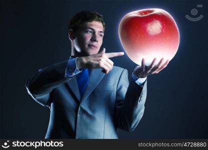 Man with apple. Young businessman holding huge apple in hand