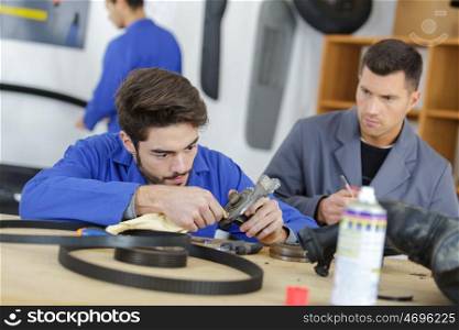 man with apprentice holding car part