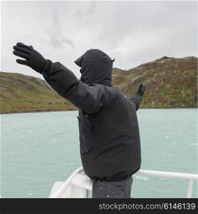 Man with arm outstretched on boat at Lake Pehoe, Torres del Paine National Park, Patagonia, Chile