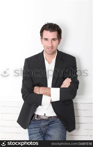 Man with arms crossed leaning on white wall