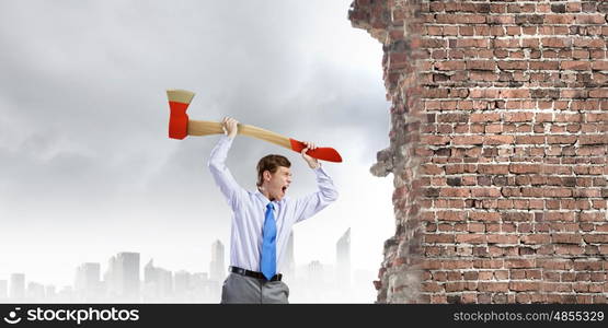 Man with axe. Young determined businessman crashing wall with axe