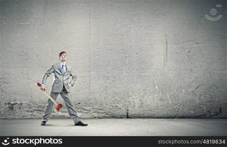 Man with axe. Young determined businessman in suit holding big axe