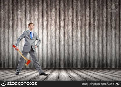 Man with axe. Young determined businessman in suit holding big axe