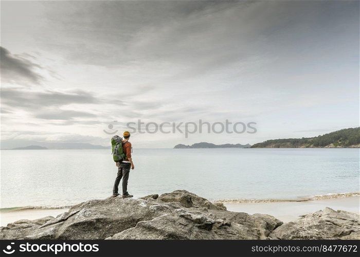 Man with backoack enjoying the morning view of the coast