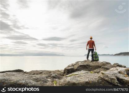 Man with backpack enjoying  the beautiful morning view of the coast