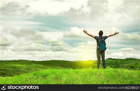 Man with backpack on a hill spreading his arms. Adventurous man spreading his arms in the countryside. Explorer man spreading his arms on a hill. Lifestyle of adventurous man in the field