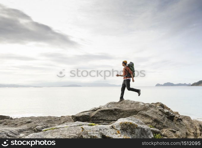 Man with backpack running over the rocks