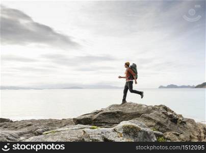 Man with backpack running over the rocks