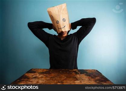 Man with bag over head relaxing at desk