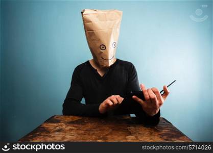 Man with bag over head using tablet
